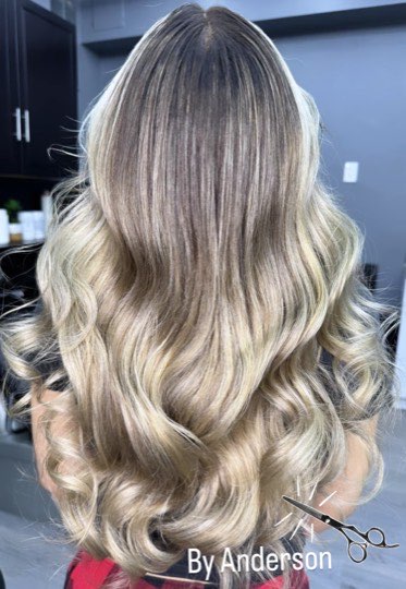 Balayage from dark roots to platinum blonde on long waves.