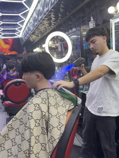 A barber drying and styling a client's hair at Morales Barbershop MB.