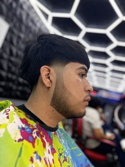 Edgar cut with a straight fringe and a taper on the sides.