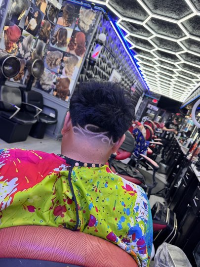 Curved lines shaved freehand on the nape over a fade.