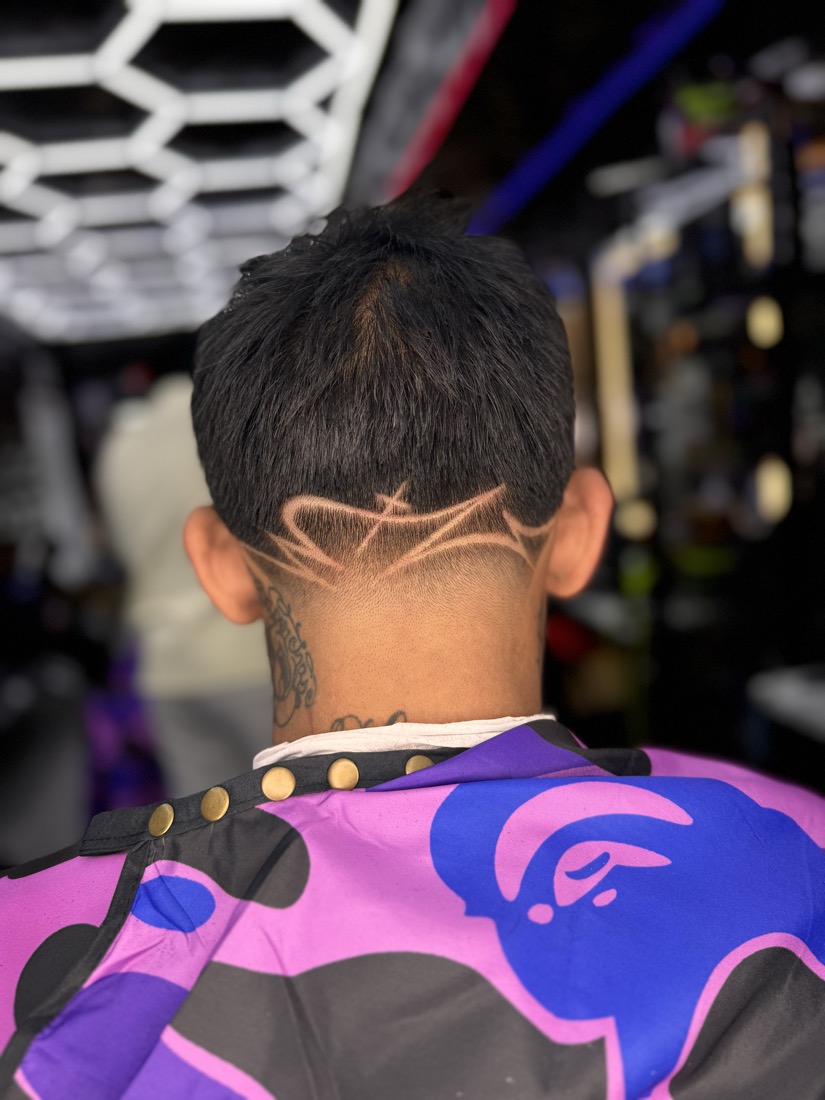 Freehand shaved lines on the nape over the fade.