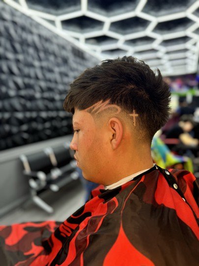 Mullet with a high fade and a cross shaved into the side.