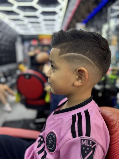 Kid with a curve shaved with a razor from the forehead to the nape over a skin fade.