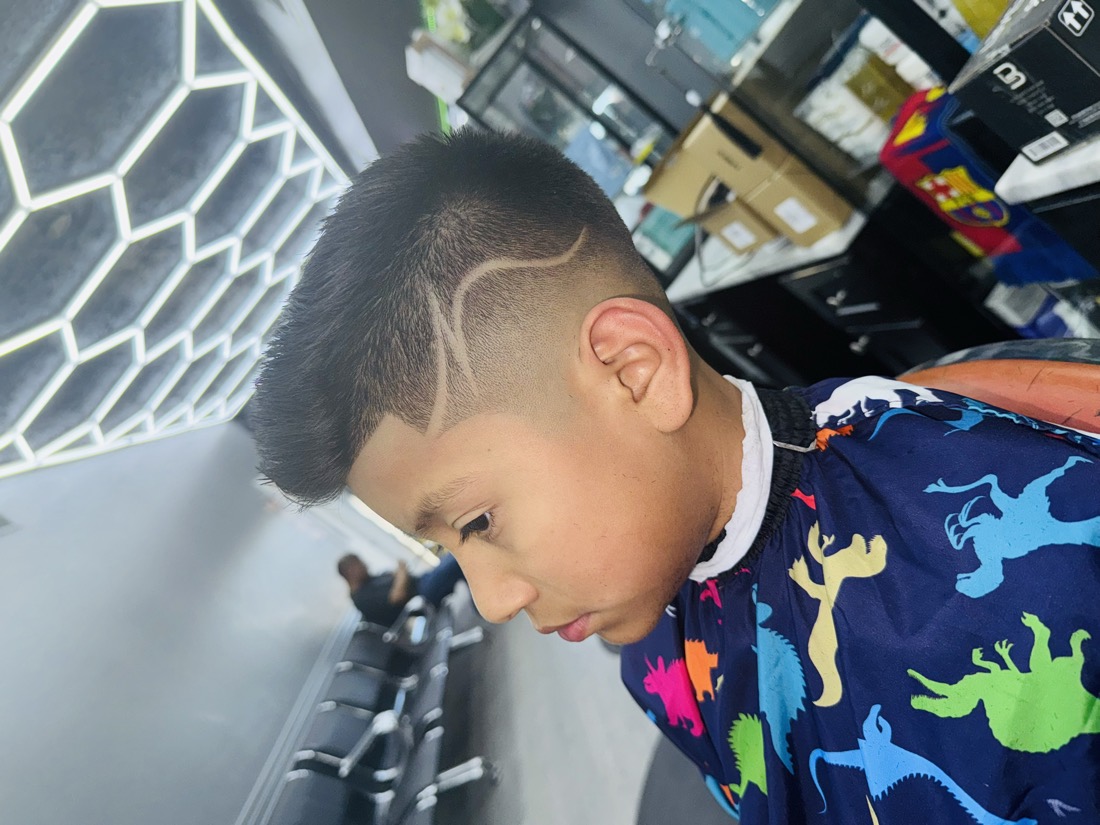 Kid with a high skin fade and a curved shaved line on the side.