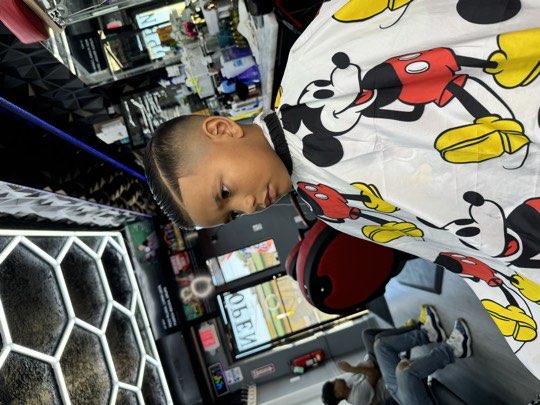 Kid with a high skin fade and a sharp line up, side view.
