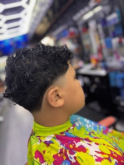 Curls on top with a skin fade on the sides, side view.