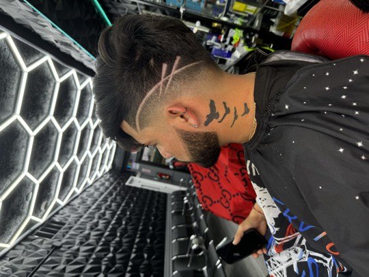 High skin fade with shaved lines on the side and a lined up beard.