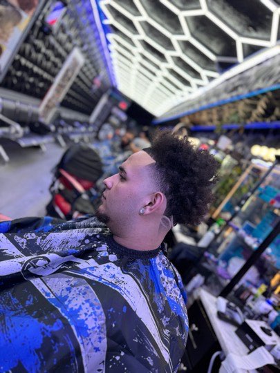 High skin fade with loose curls on top, side view.