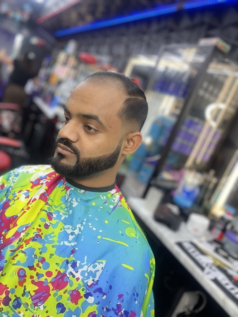 Skin fade with a full beard and a line up on the forehead.