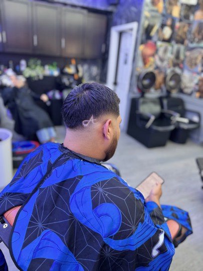 Skin fade with a trimmed beard and a shaved line on the side.