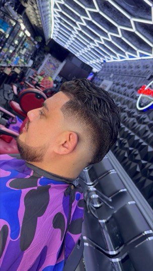 Skin fade with the hair combed back and a lined up beard.