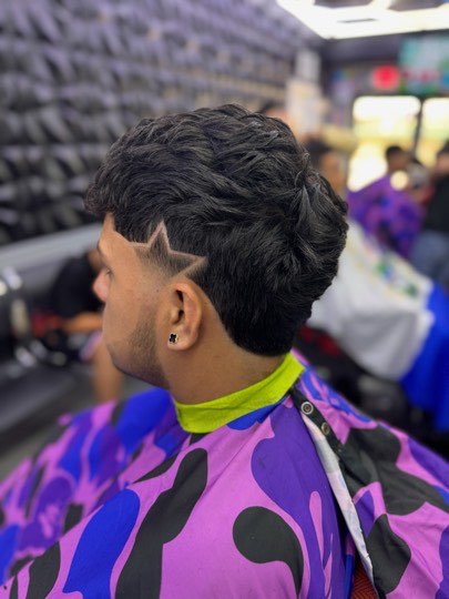 Skin fade with the part shaved in and loose curls on top.