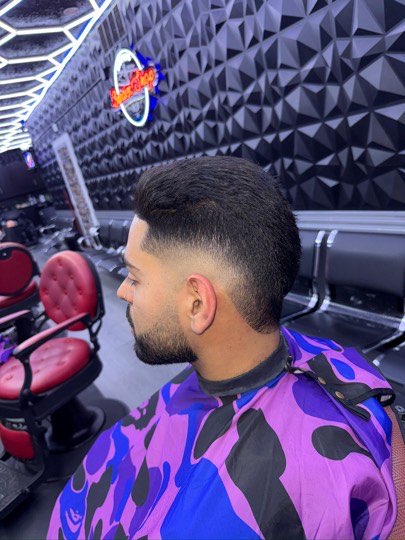 Skin fade with volume on top and a lined up beard, side view.