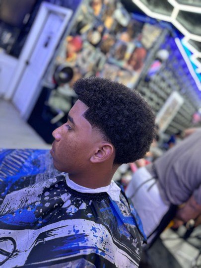 Taper fade around the ear with an afro on top.