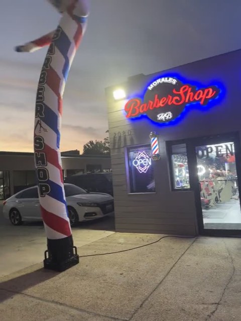 Video: the front and neon sign of Morales Barbershop MB at night.